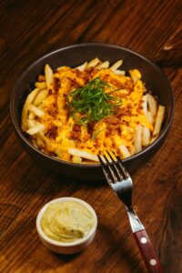 Delicious cheesy fries topped with bacon bits and chives, served with a creamy dipping sauce.